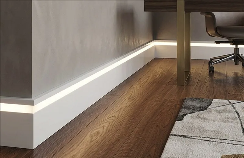 Rodapé branco com suporte para LED aceso, instalado em sala com piso de madeira